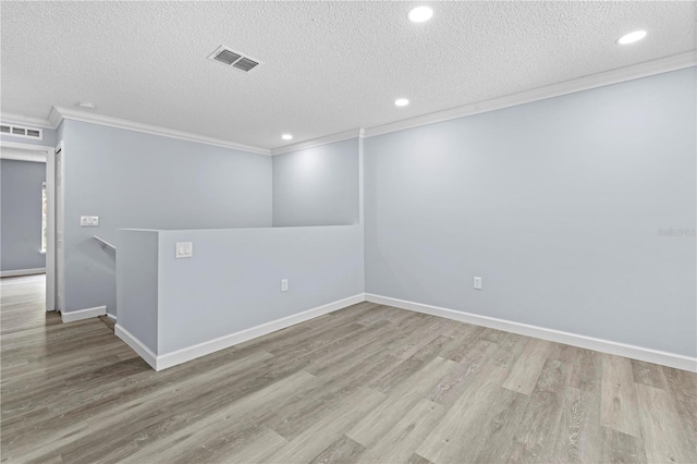 unfurnished room with crown molding, light hardwood / wood-style floors, and a textured ceiling