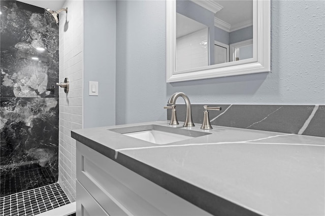 bathroom with a tile shower, vanity, and crown molding