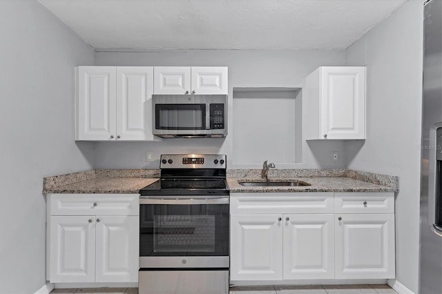 kitchen featuring light stone countertops, appliances with stainless steel finishes, white cabinets, and sink