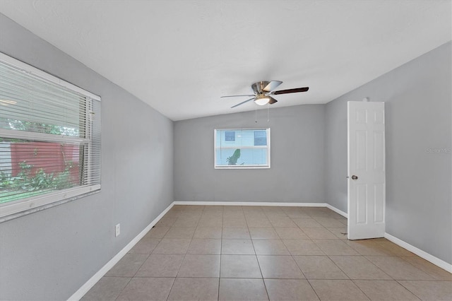 spare room with a wealth of natural light, light tile patterned flooring, and vaulted ceiling