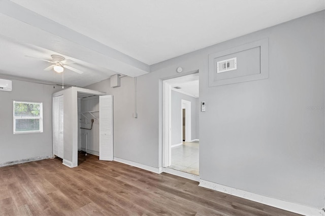 unfurnished bedroom featuring an AC wall unit, ceiling fan, and hardwood / wood-style floors