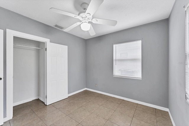 unfurnished bedroom with ceiling fan, a closet, light tile patterned floors, and crown molding