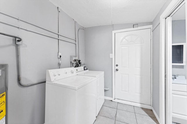 clothes washing area featuring light tile patterned floors, a textured ceiling, separate washer and dryer, and water heater