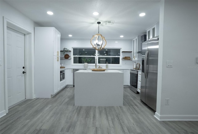 kitchen with a center island, hanging light fixtures, light hardwood / wood-style flooring, white cabinets, and appliances with stainless steel finishes