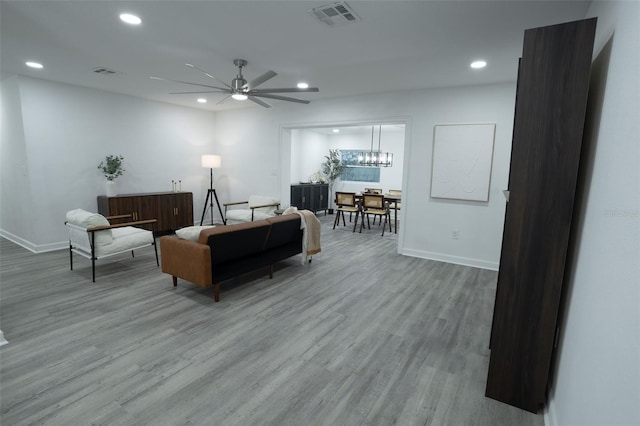 living room featuring light hardwood / wood-style flooring and ceiling fan with notable chandelier