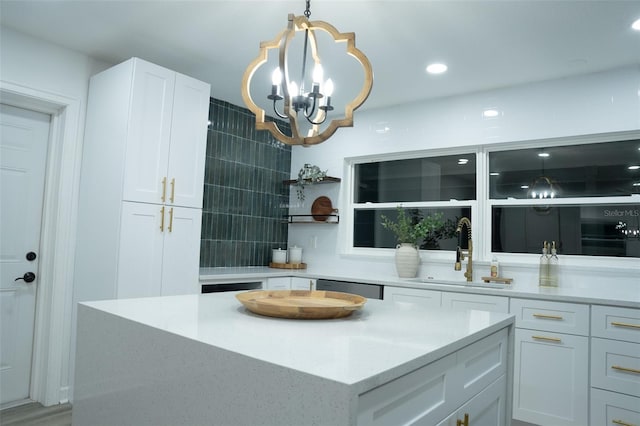 kitchen featuring sink, decorative light fixtures, dishwasher, white cabinets, and a center island