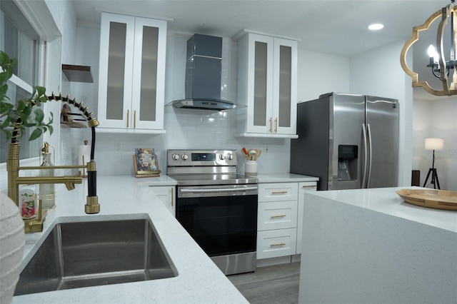 kitchen featuring tasteful backsplash, stainless steel appliances, wall chimney range hood, hardwood / wood-style flooring, and white cabinets