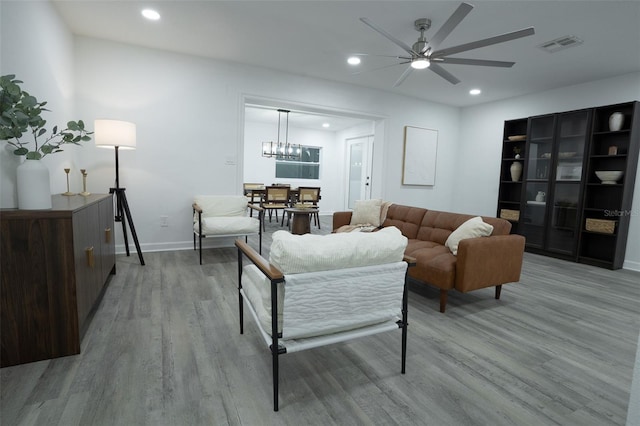 living room featuring ceiling fan with notable chandelier and hardwood / wood-style flooring