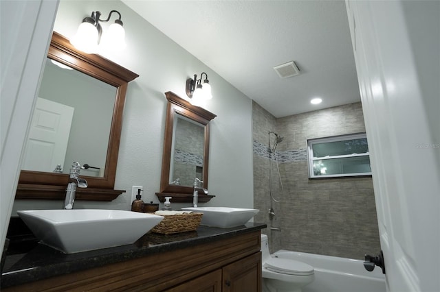 full bathroom featuring toilet, vanity, and tiled shower / bath