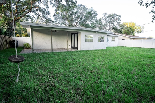 back of property featuring a lawn and ceiling fan