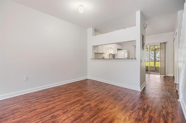 unfurnished living room with dark hardwood / wood-style floors, sink, and a textured ceiling