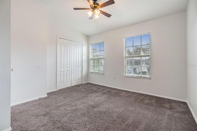 unfurnished bedroom with dark colored carpet, ceiling fan, lofted ceiling, and a closet