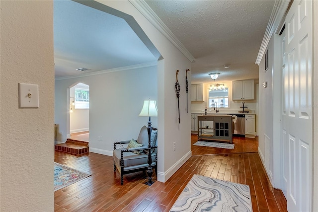 hall with light hardwood / wood-style flooring, a healthy amount of sunlight, and crown molding