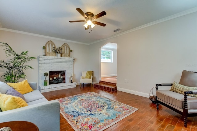 living room with hardwood / wood-style flooring, a fireplace, ceiling fan, and crown molding