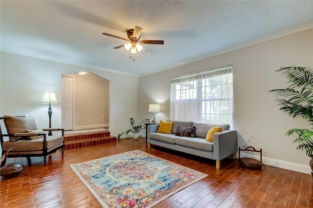 living room featuring a textured ceiling, ceiling fan, crown molding, and dark wood-type flooring