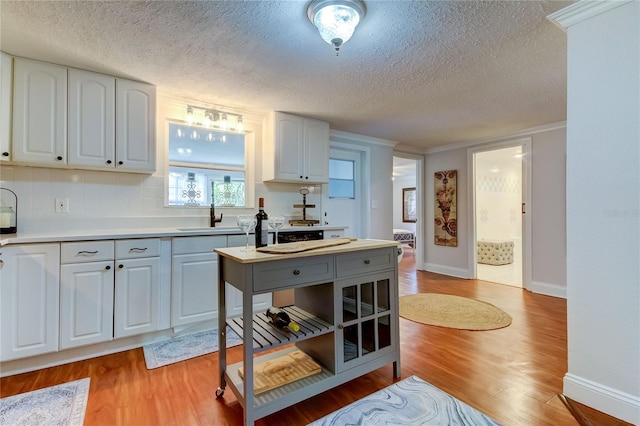 kitchen with white cabinets, light wood-type flooring, sink, and a textured ceiling