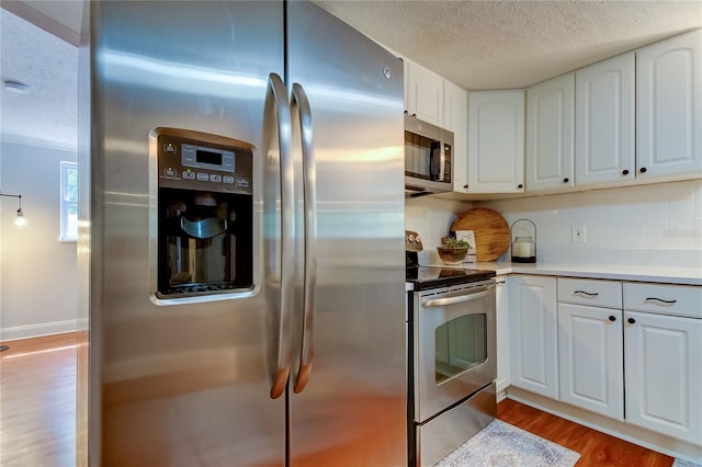 kitchen with decorative backsplash, white cabinetry, appliances with stainless steel finishes, and light hardwood / wood-style flooring