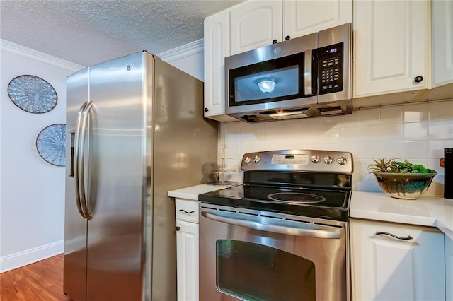 kitchen with backsplash, dark hardwood / wood-style floors, ornamental molding, appliances with stainless steel finishes, and white cabinetry