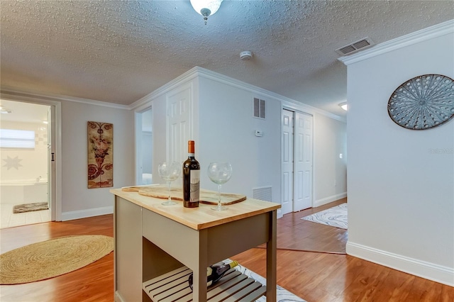 kitchen with a textured ceiling, hardwood / wood-style flooring, and crown molding