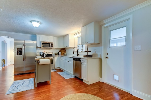 kitchen featuring white cabinets, a kitchen island, light wood-type flooring, and stainless steel appliances