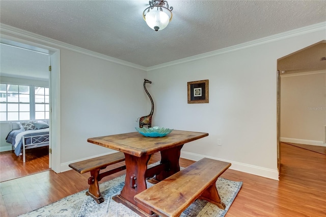 dining area featuring crown molding, light hardwood / wood-style flooring, and a textured ceiling