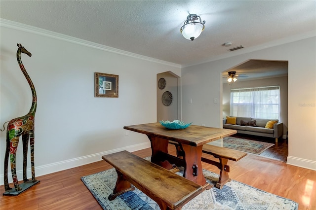 dining room featuring a textured ceiling, ceiling fan, ornamental molding, and dark wood-type flooring