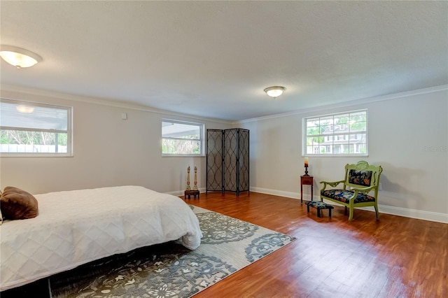 bedroom featuring wood-type flooring, ornamental molding, and multiple windows