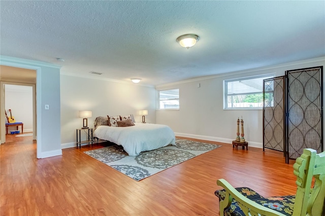 bedroom featuring crown molding, hardwood / wood-style floors, and a textured ceiling