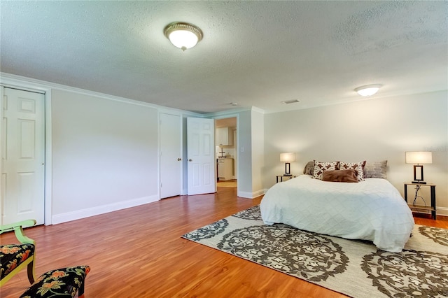 bedroom featuring hardwood / wood-style flooring, crown molding, and a textured ceiling