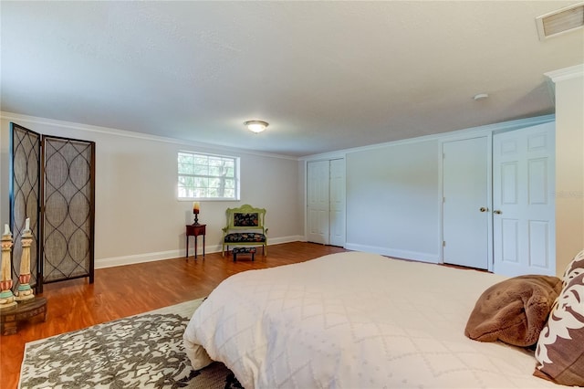 bedroom featuring a closet, wood-type flooring, a textured ceiling, and ornamental molding