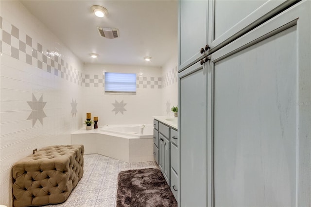 bathroom featuring vanity, a relaxing tiled tub, and tile patterned floors