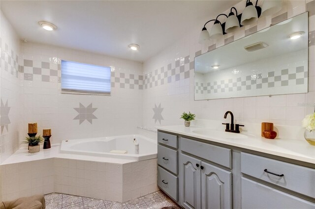 bathroom with vanity, tasteful backsplash, tile walls, and a relaxing tiled tub