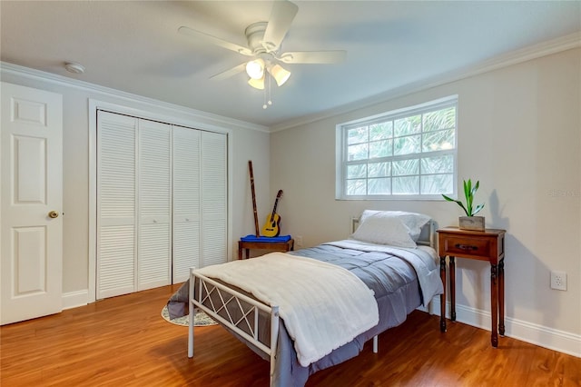 bedroom with hardwood / wood-style floors, ceiling fan, crown molding, and a closet