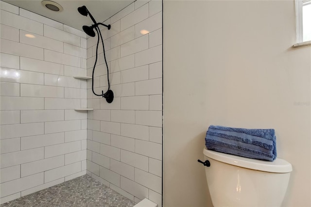 bathroom with a tile shower and toilet