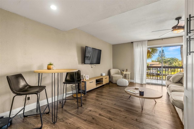 living room with ceiling fan and dark wood-type flooring