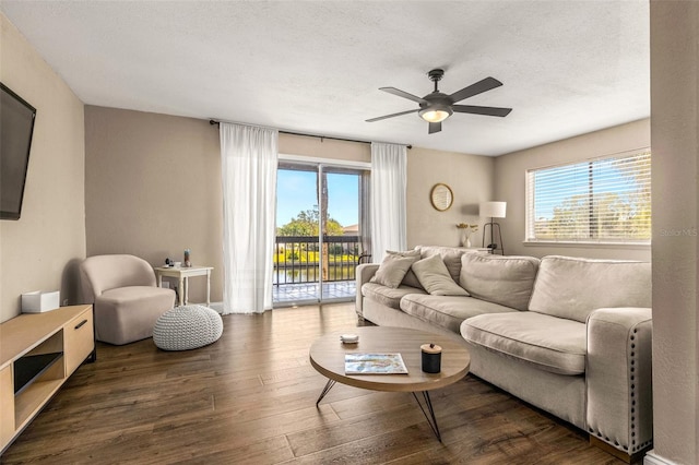 living room featuring ceiling fan, a healthy amount of sunlight, dark hardwood / wood-style flooring, and a textured ceiling