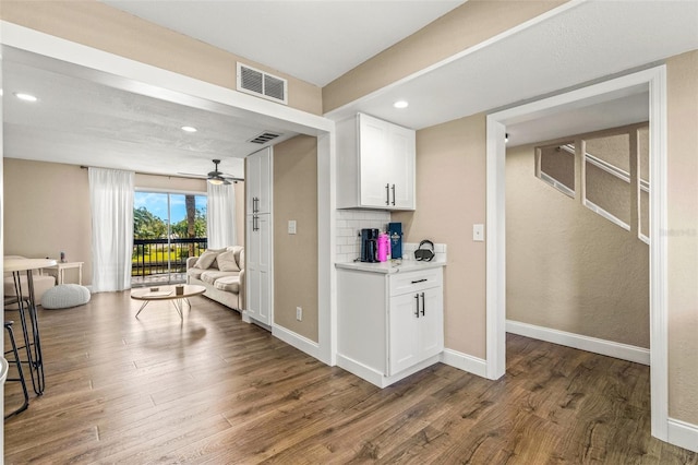 interior space with white cabinetry, ceiling fan, dark hardwood / wood-style floors, and tasteful backsplash