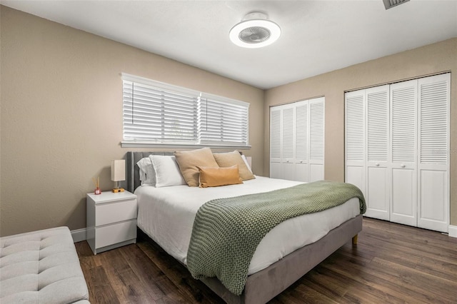 bedroom with dark hardwood / wood-style flooring and multiple closets