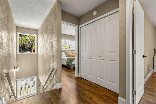 hallway with a textured ceiling and dark hardwood / wood-style floors