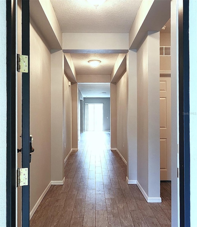 hallway with a textured ceiling and hardwood / wood-style flooring