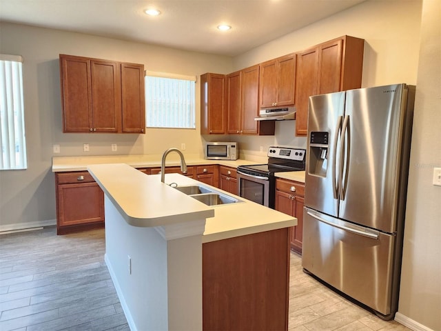 kitchen with sink, an island with sink, light hardwood / wood-style flooring, and appliances with stainless steel finishes