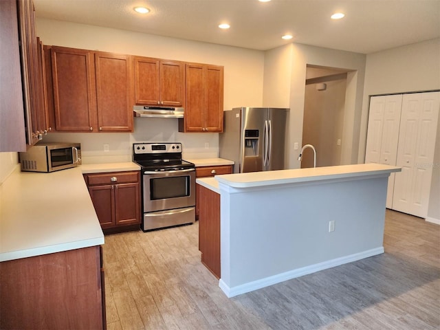 107 Slipper Key Rd, Apollo Beach, FL 33572 - kitchen with stainless steel appliances, under cabinet range hood, light wood-style floors, light countertops, and brown cabinetry