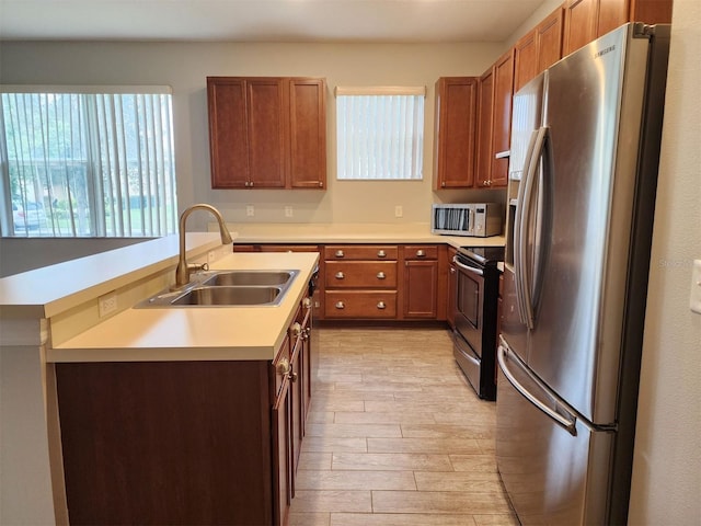 kitchen with appliances with stainless steel finishes, light hardwood / wood-style flooring, a healthy amount of sunlight, and sink