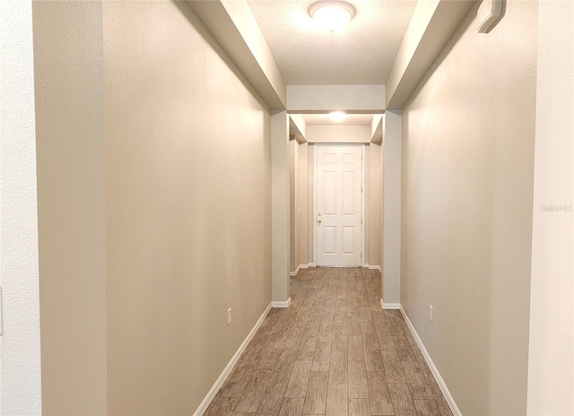 hall with wood-type flooring and a textured ceiling