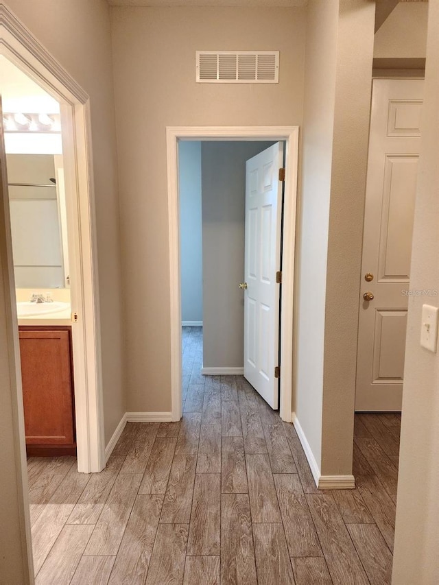 hall with light hardwood / wood-style floors and sink