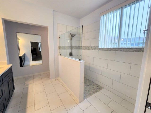 bathroom with tile patterned flooring, vanity, and tiled shower