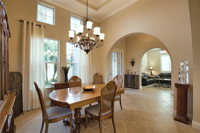 tiled dining room featuring plenty of natural light, ornamental molding, a chandelier, and a high ceiling