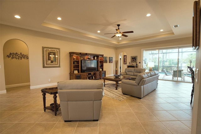 tiled living room featuring a raised ceiling, crown molding, and ceiling fan