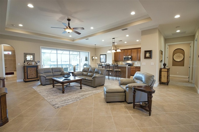 living room with light tile patterned flooring, ceiling fan, and a tray ceiling