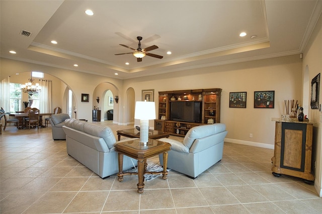 tiled living room featuring a raised ceiling, crown molding, and ceiling fan with notable chandelier